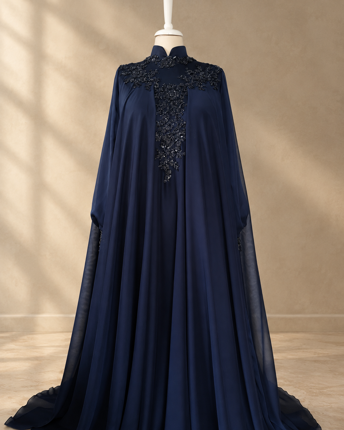 Dina navy gown at an angle: black beads and sequins at the collar and centre front, chiffon cape sleeves falling to the hem