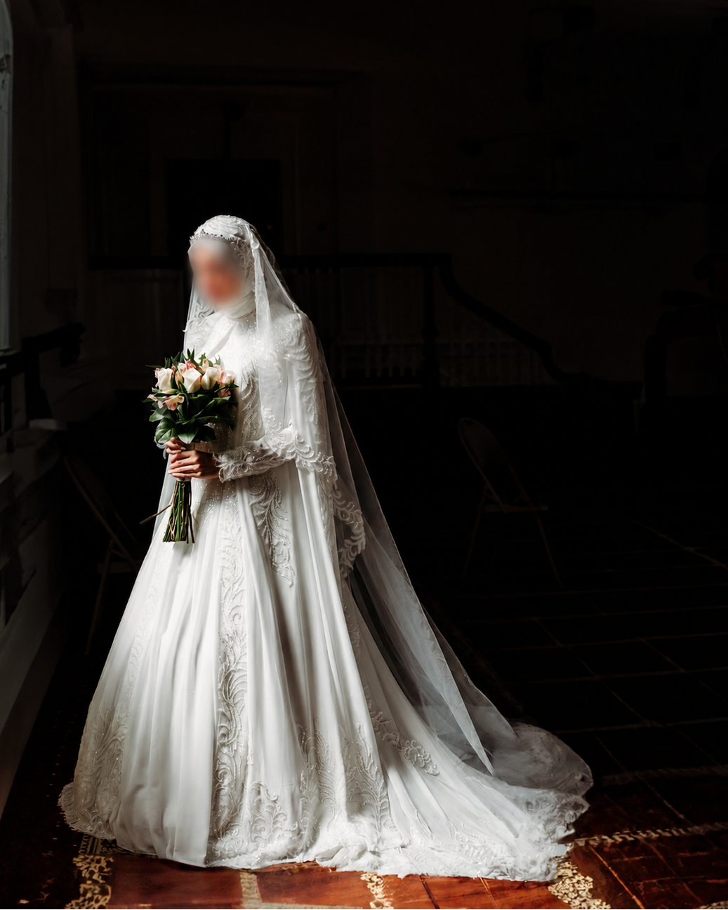 Person in a white wedding dress holding a bouquet in a dimly lit room.