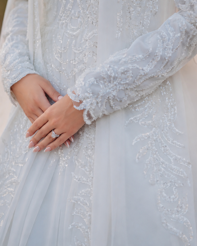 Close-up of a person wearing a lace wedding dress with a blurred natural background