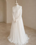A white long-sleeve maxi dress with a textured embroidered bodice, high collar, and flowing chiffon skirt, displayed on a mannequin in a neutral indoor setting.
