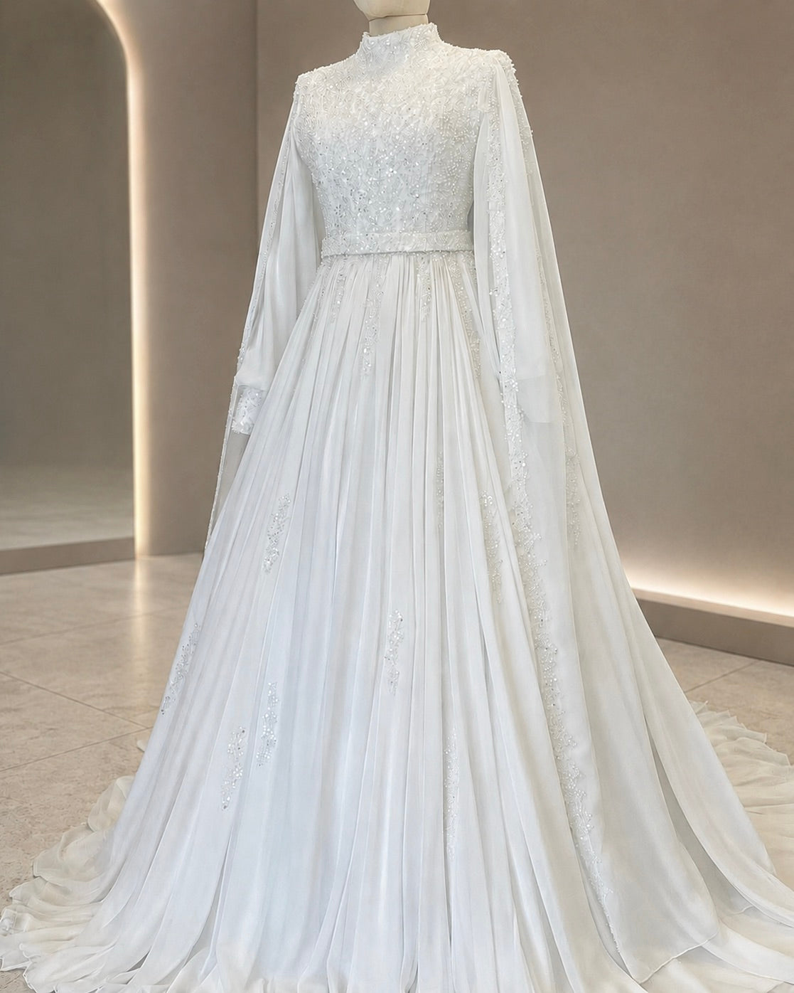 White wedding dress with long sleeves and a flowing skirt on a mannequin against a neutral background.