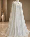 White lace cape on a mannequin against a beige wall with a vase in the background.